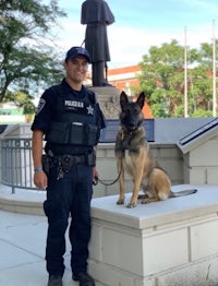 a police officer and a german shepherd standing next to a statue
